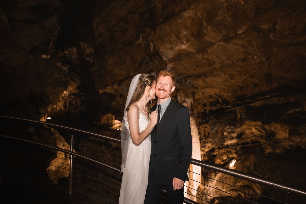A couple shares an intimate moment during their wedding celebration in a dimly lit cave setting.