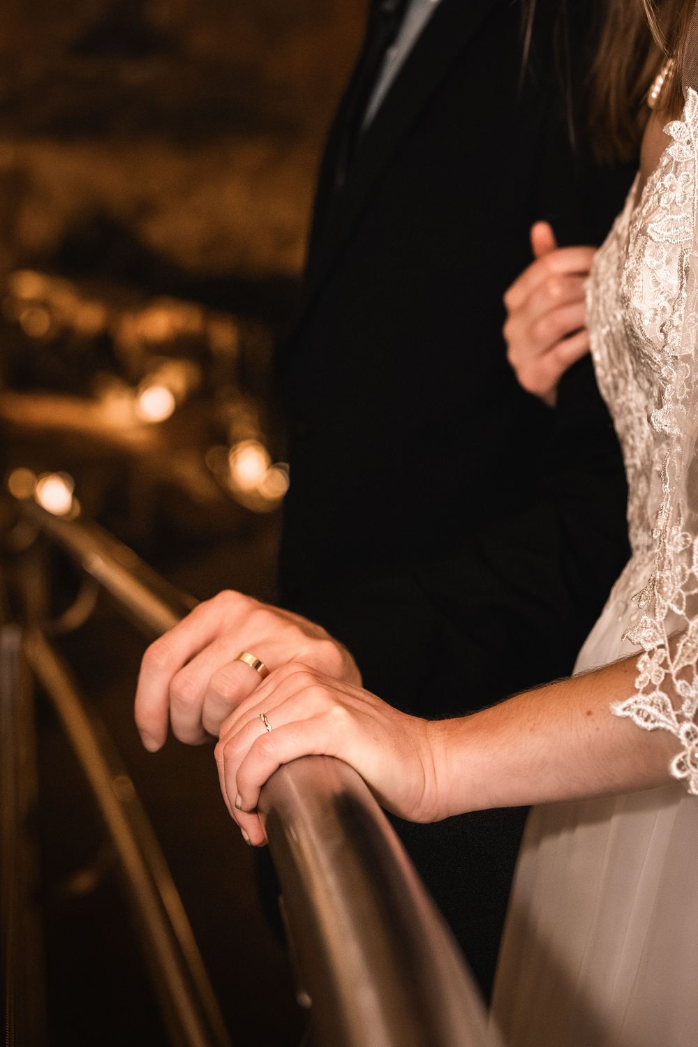 A close-up view of hands resting on a white chair back in warm lighting at an elegant event.