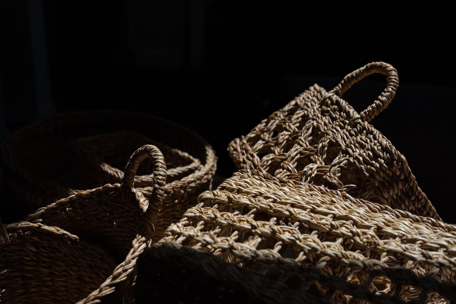 Handwoven wicker storage baskets photographed in dramatic studio lighting for homeware brand photography