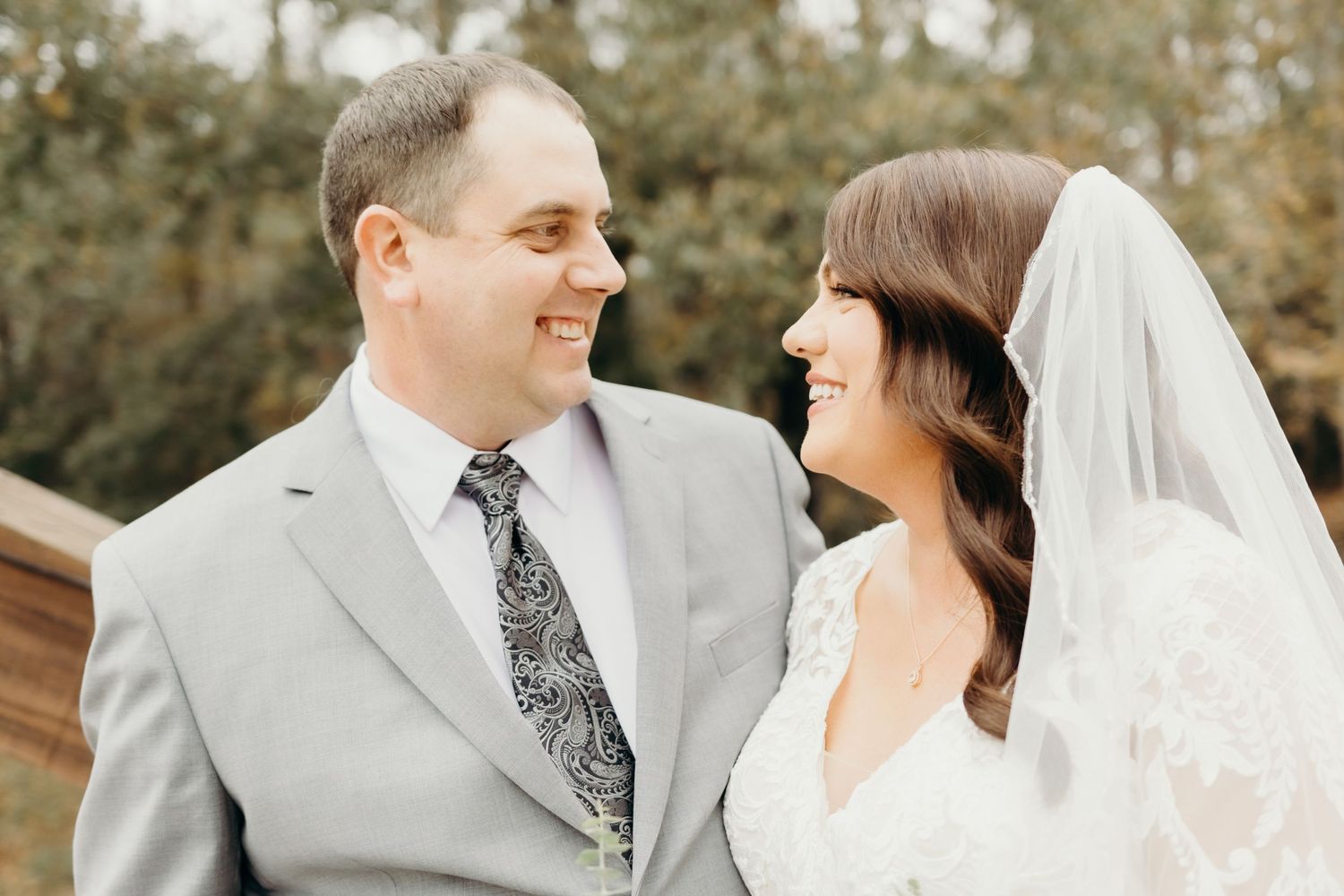 Wedding couple sharing intimate moments in an outdoor setting wearing grey and white attire.