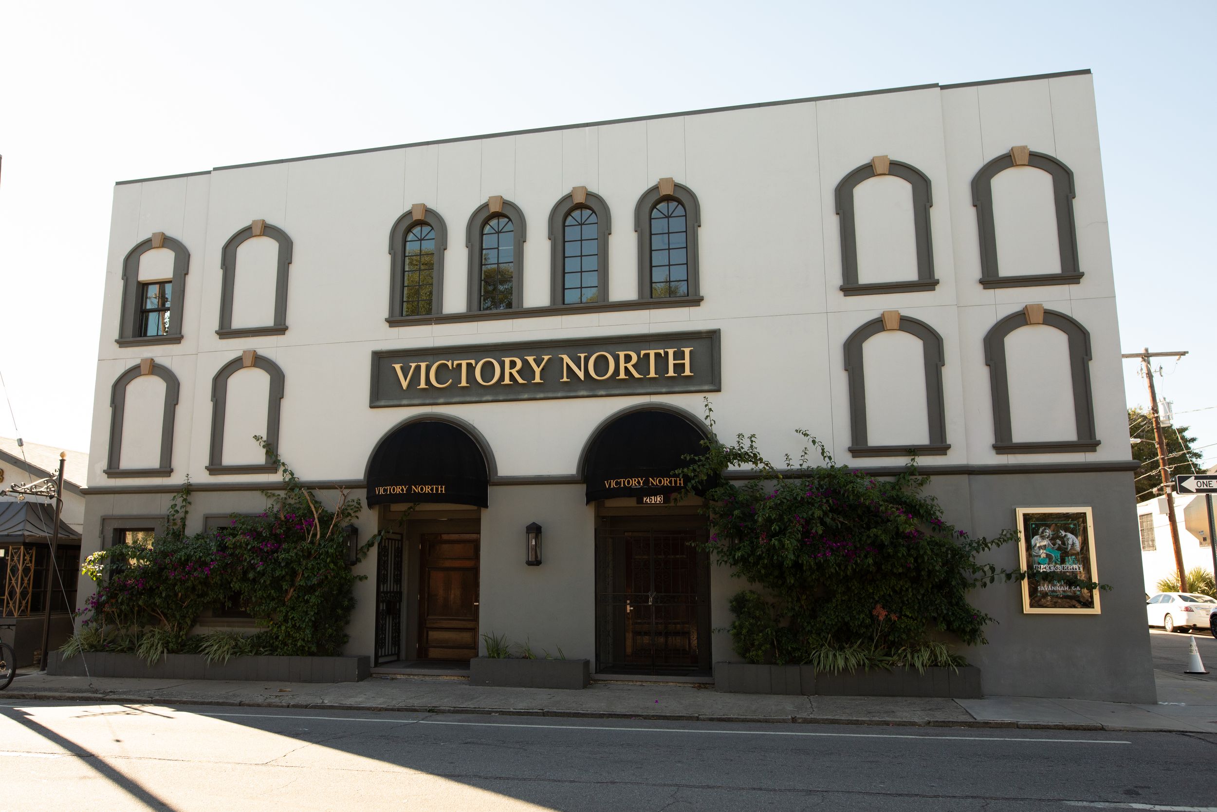 A white commercial building with arched windows and a 'Victory North' sign mounted on its facade.