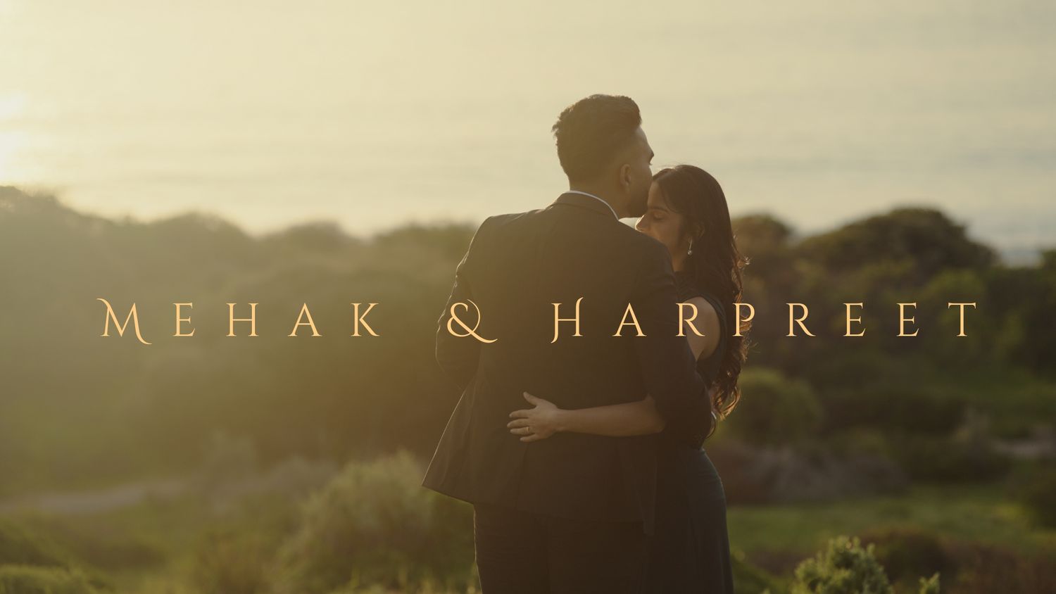 A couple embraces in silhouette against a warm sunset backdrop with mountains and greenery in the distance.