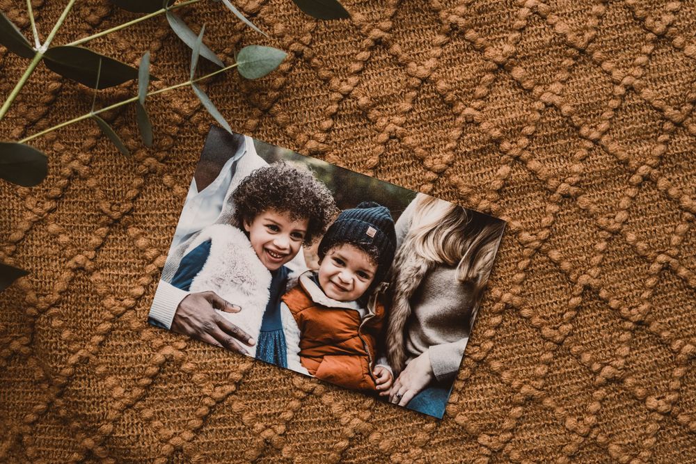 A husky dog and a young child play together on reddish-brown dirt ground while smiling and having fun.