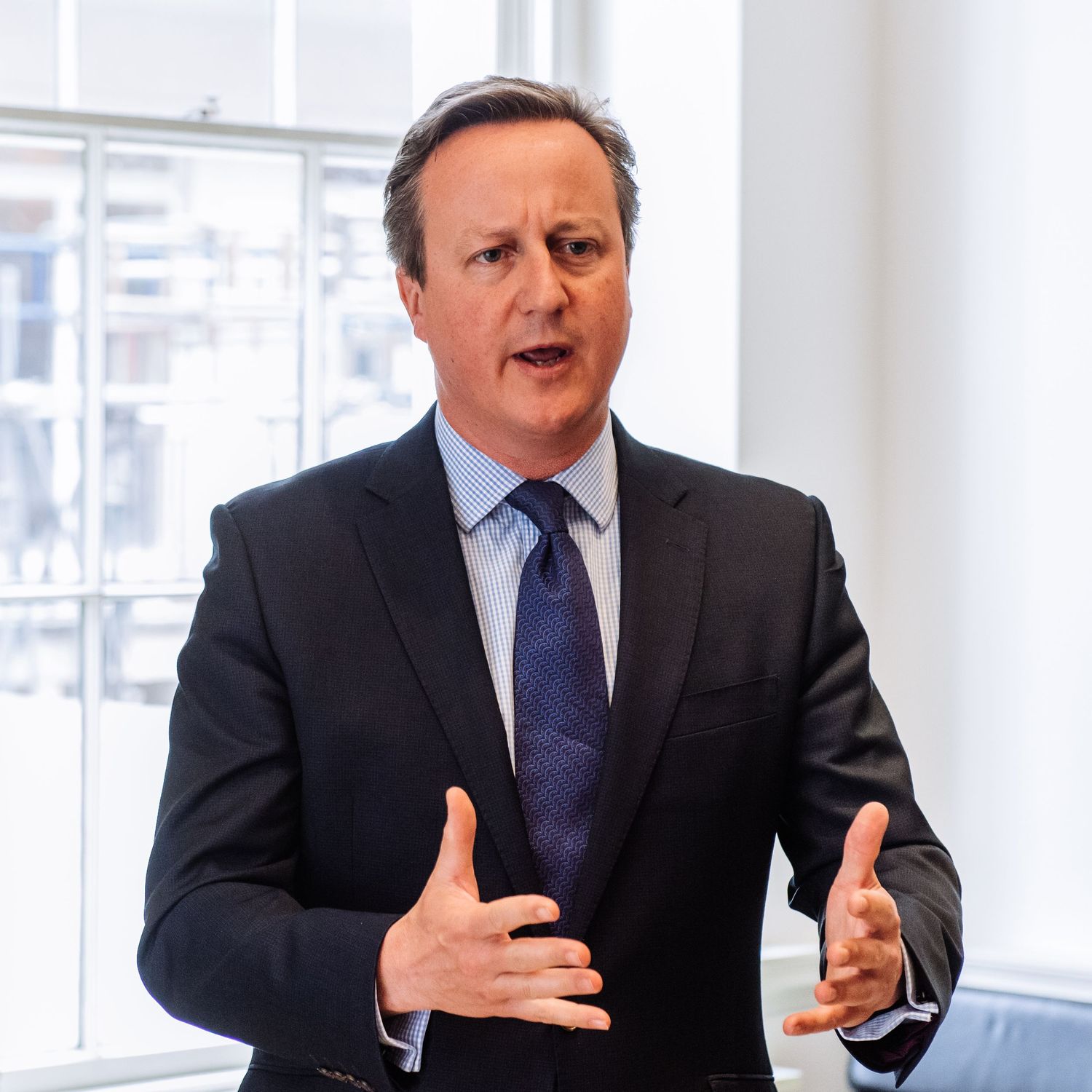 Executive gesturing while speaking in a bright modern office space.