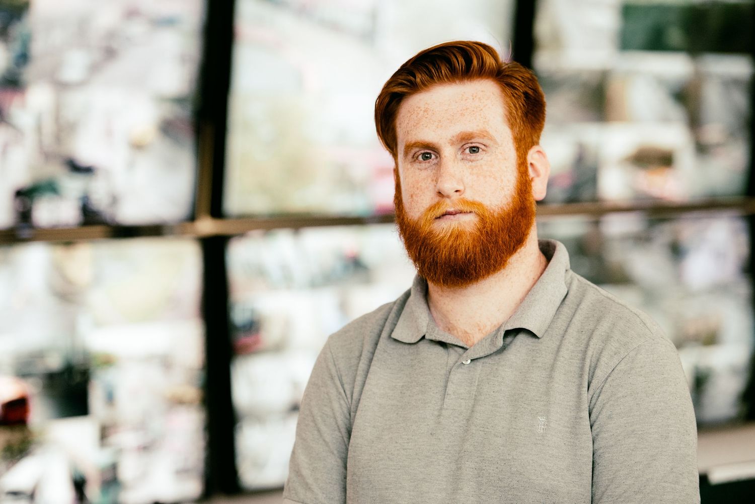 Professional headshot of person with red beard wearing grey polo shirt.
