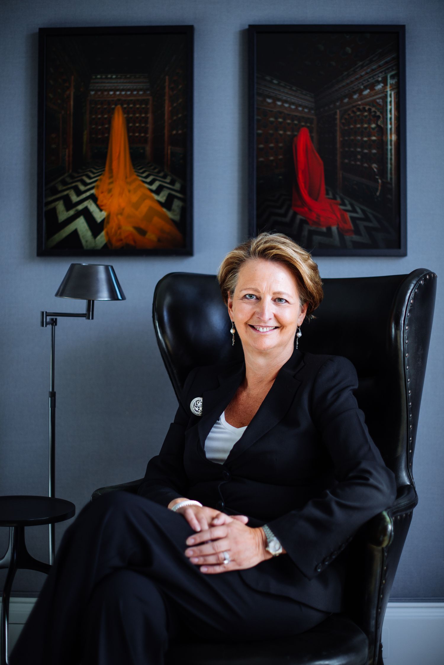 Executive seated in leather chair with modern art prints displayed on wall behind.