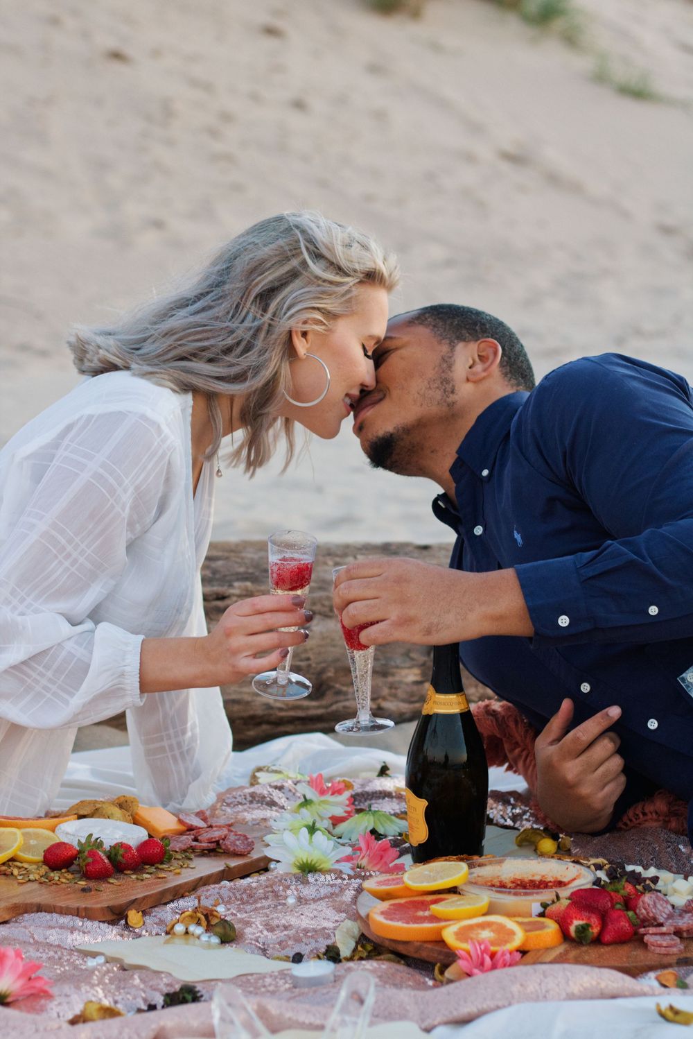 A couple leaning in for a kiss at a beach picnic