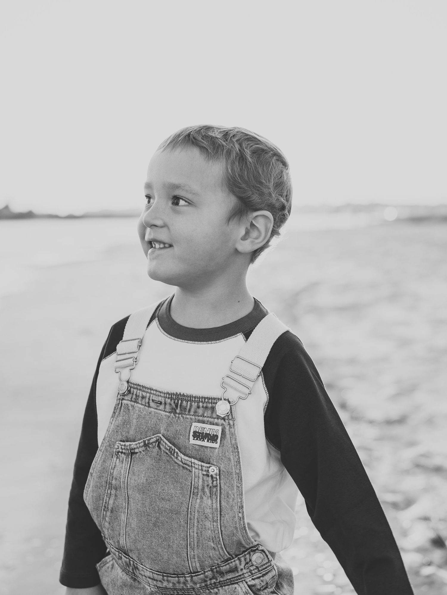 Close-up of toddler boy on the beach looking out at the water in ocean county, nj.