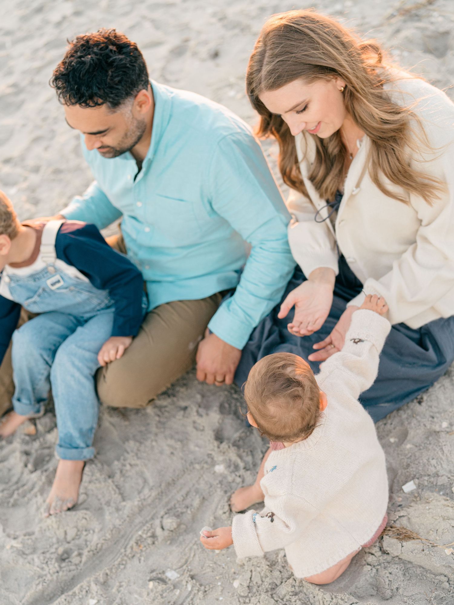 Close-up of family hands intertwined on the beach.