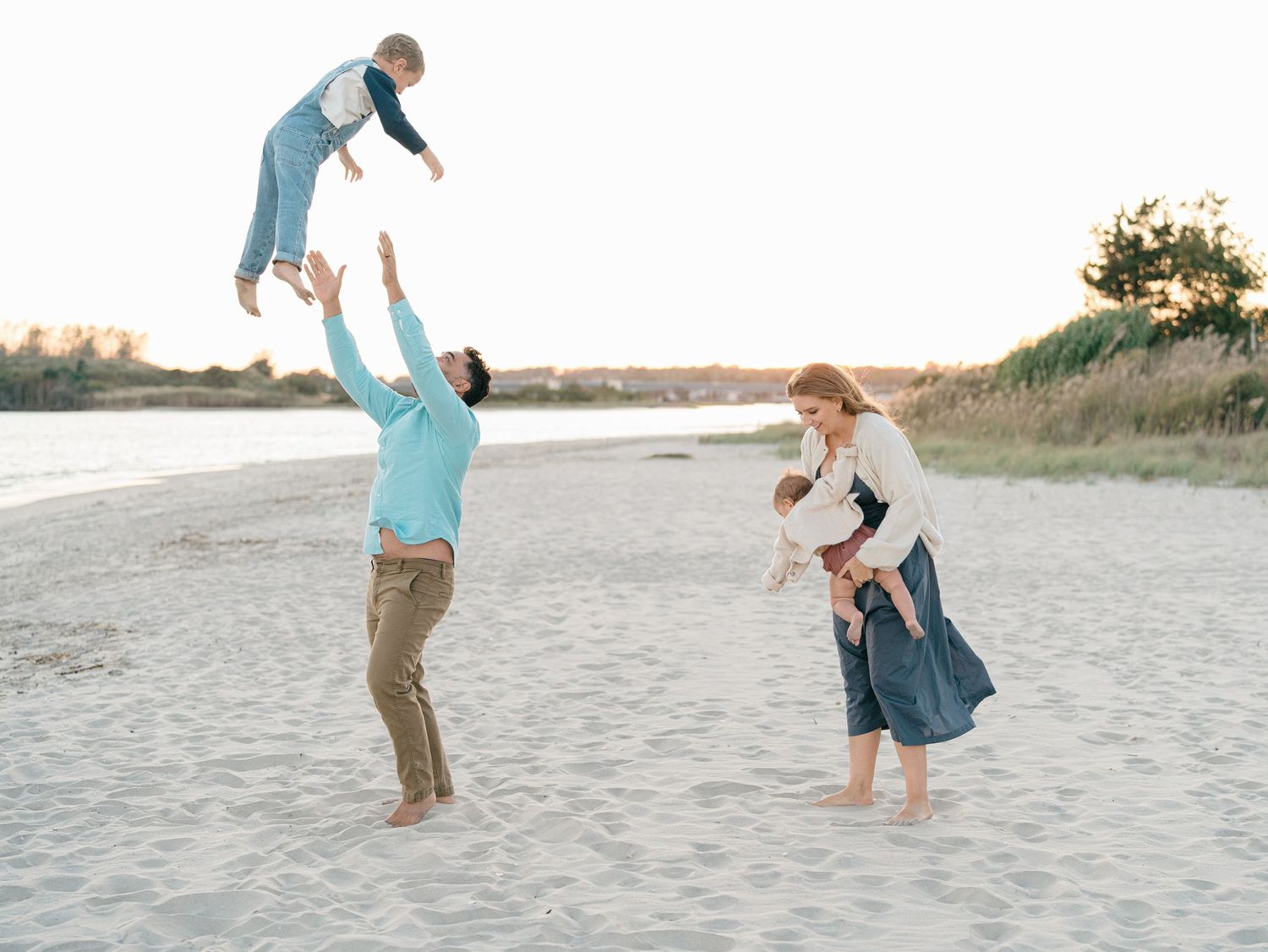 Parent lifting child in the air during a beach family session.
