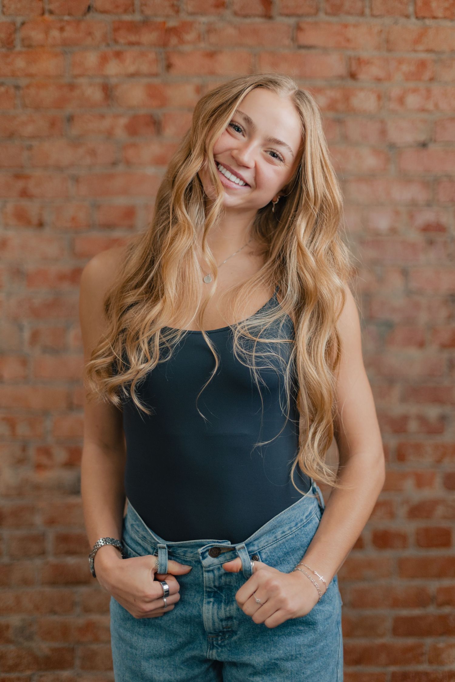 A series of candid lifestyle portraits against a rustic brick wall background showing casual denim style.