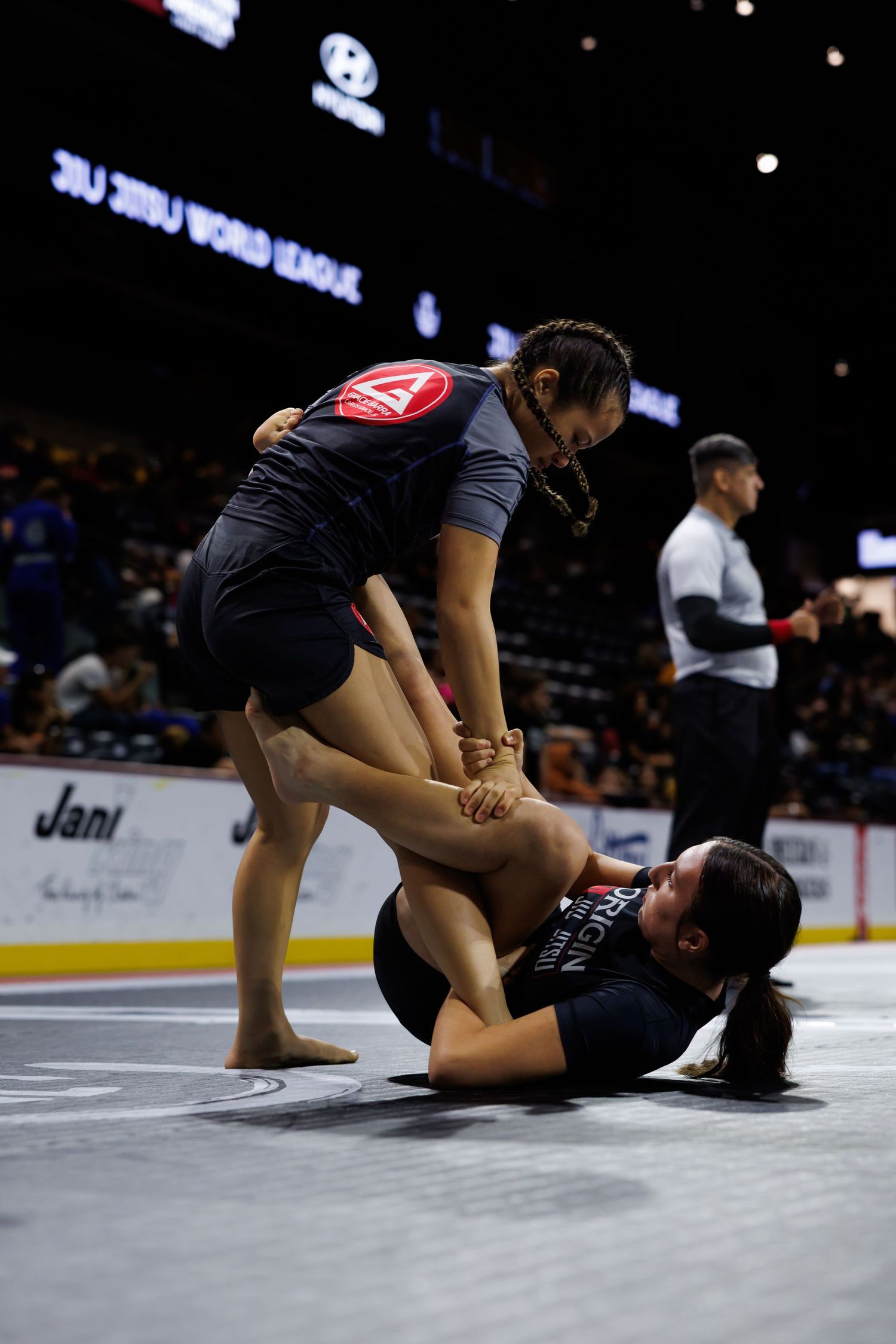 Two martial artists engaged in ground combat during a competition match.