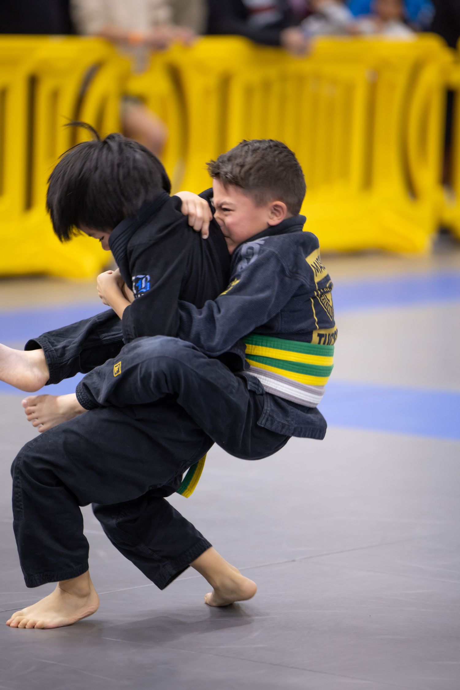 Young martial arts student in black gi performing dynamic throw technique.