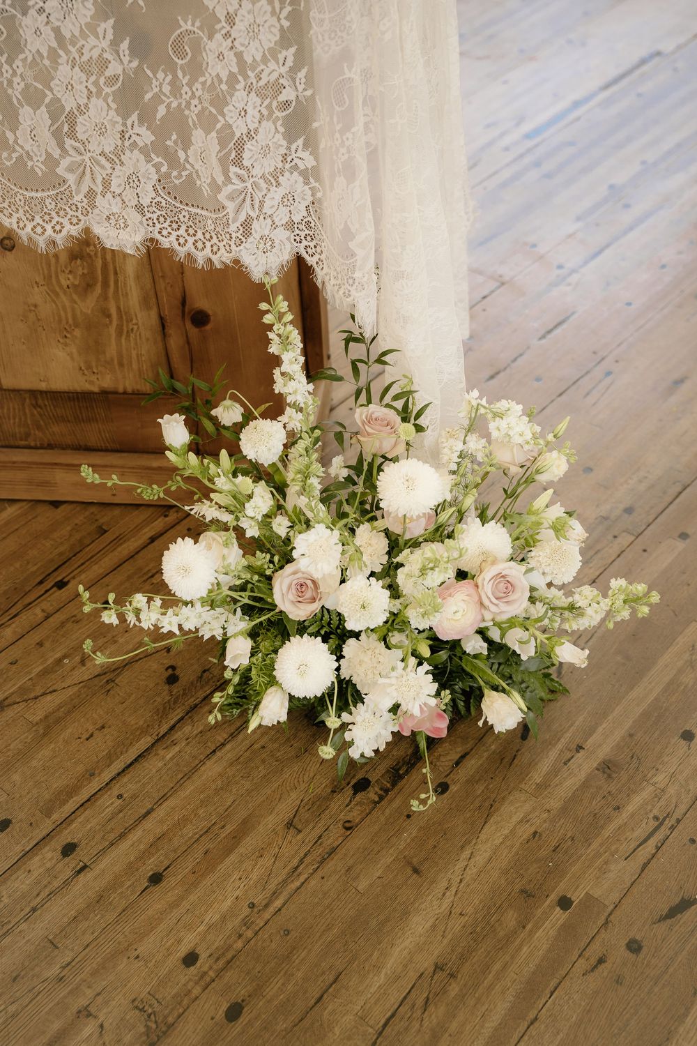 Elegant floral arrangement with white and pink roses on wooden flooring.