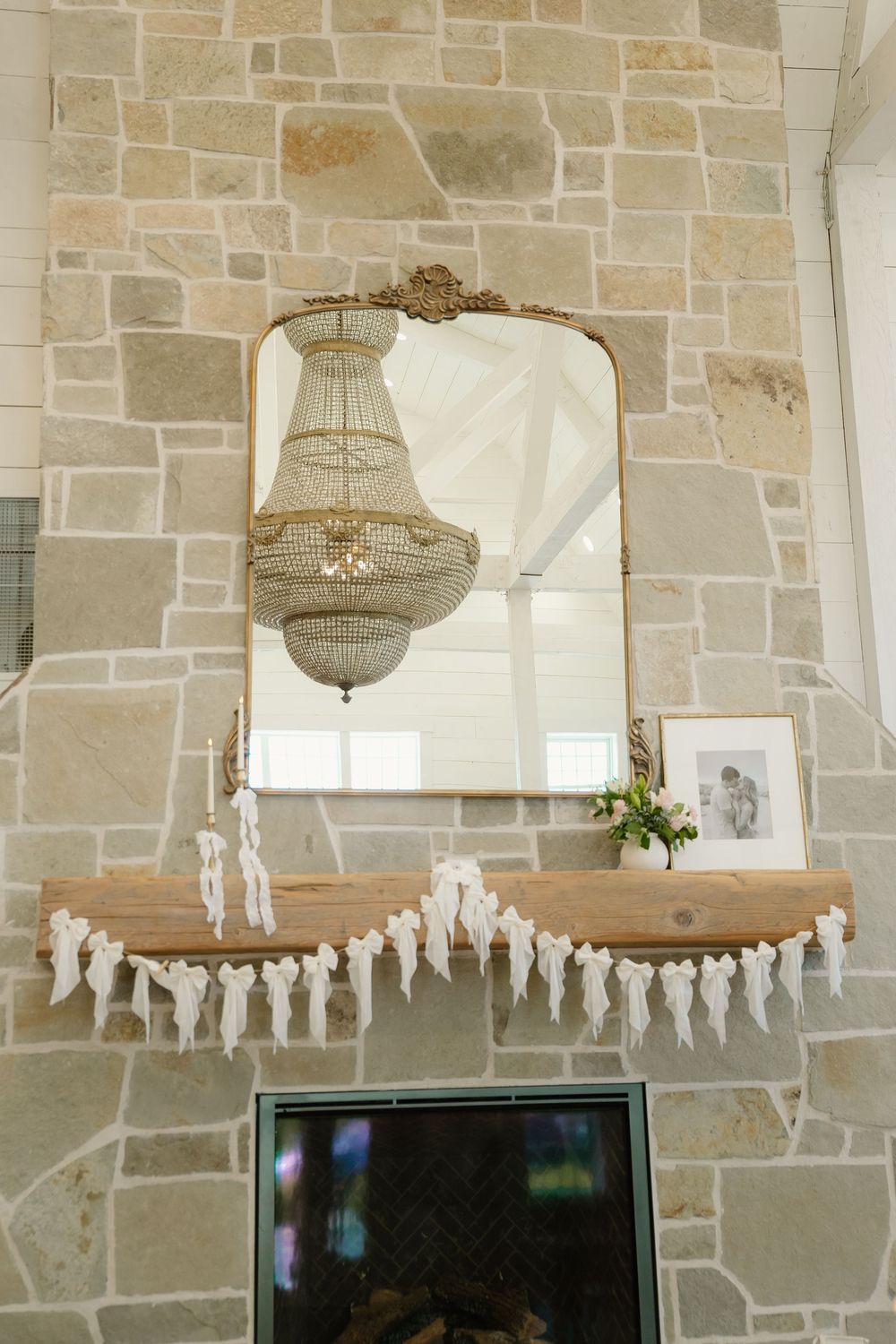 Crystal chandeliers and paper angel decorations adorn stone wall at wedding venue.