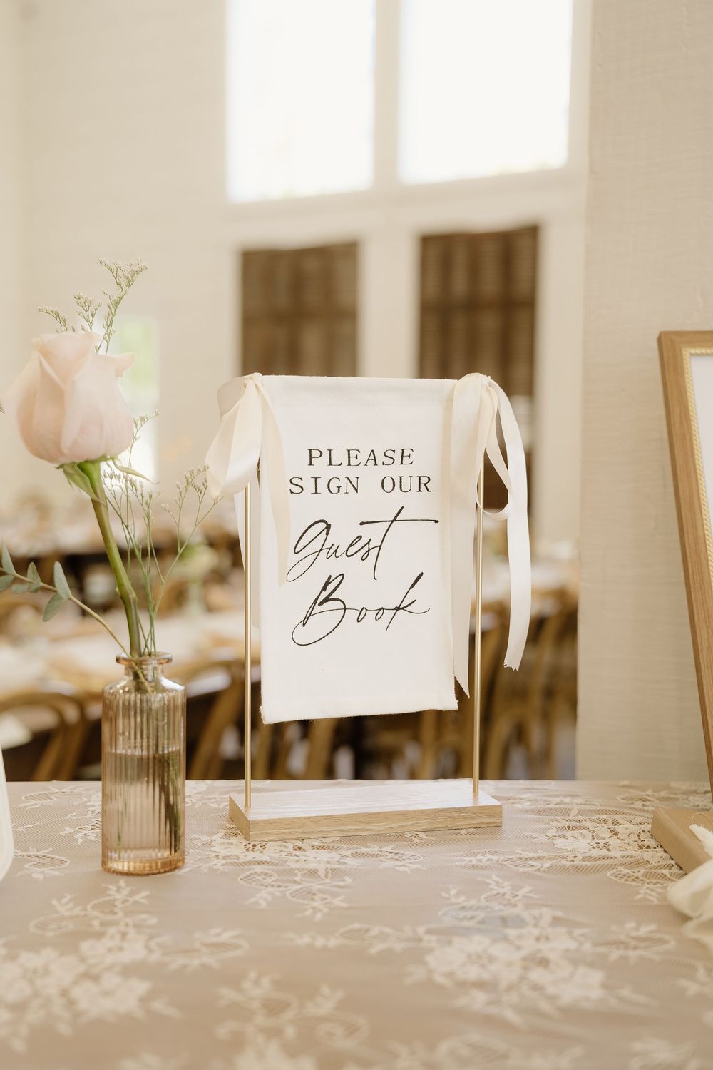 Wedding guest book sign display with elegant calligraphy on white tablecloth.