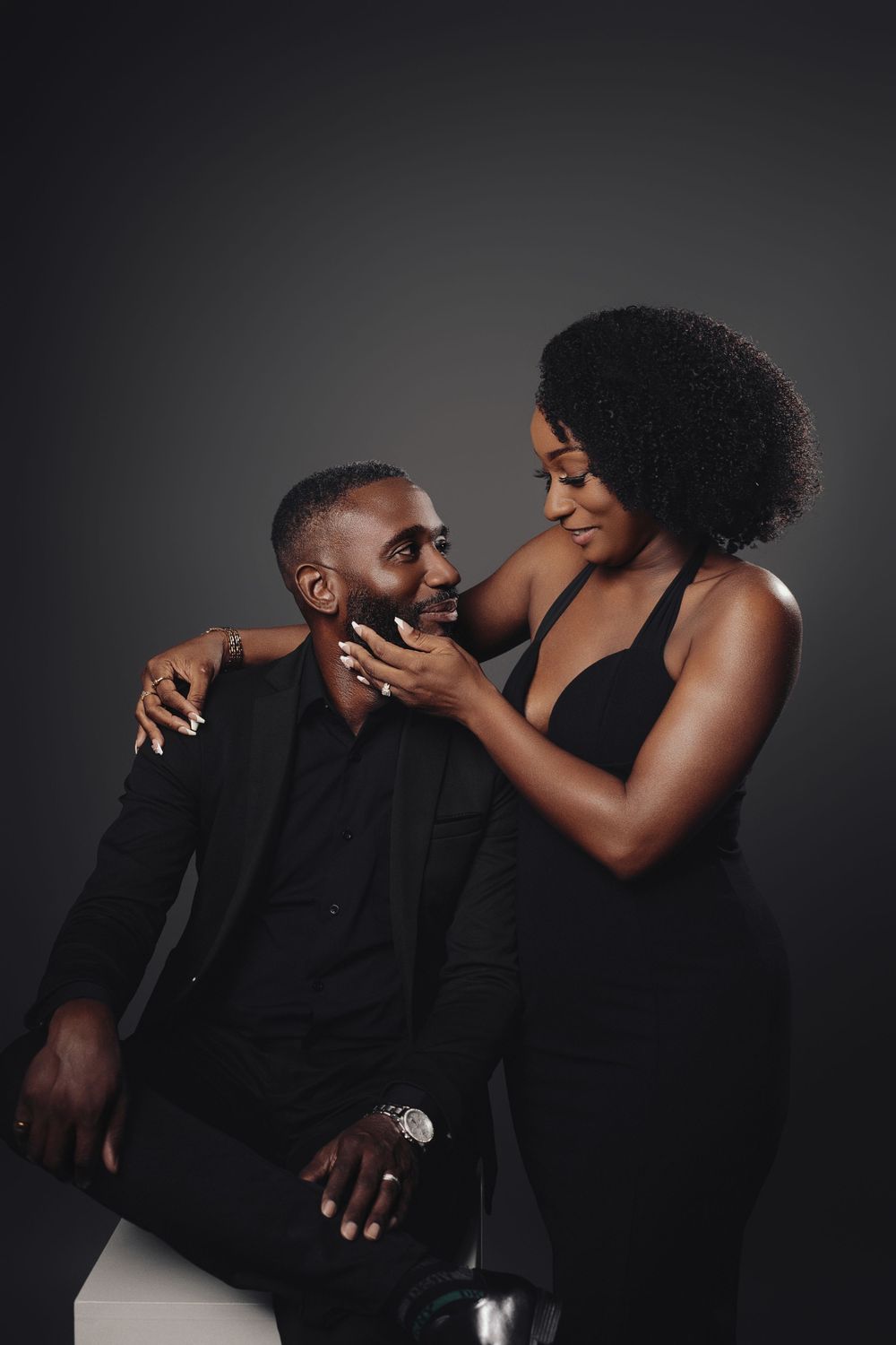 A couple shares an intimate moment during a dramatic black and white photoshoot.
