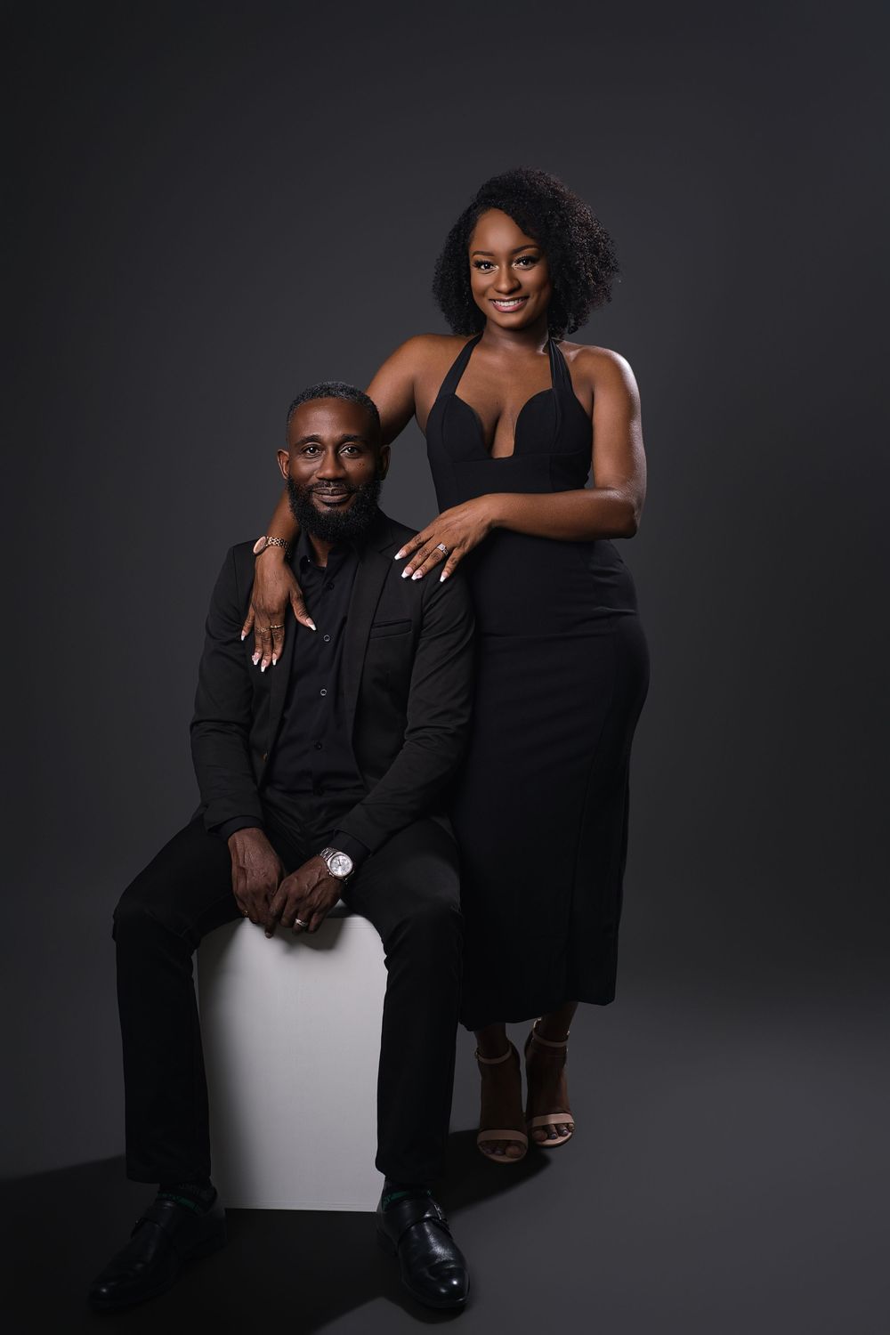 Professional studio portrait session featuring a couple in elegant black attire against dark background.