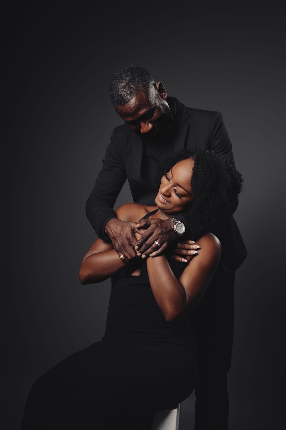 Intimate artistic black and white photo series showing tender embrace between two figures against dark background.