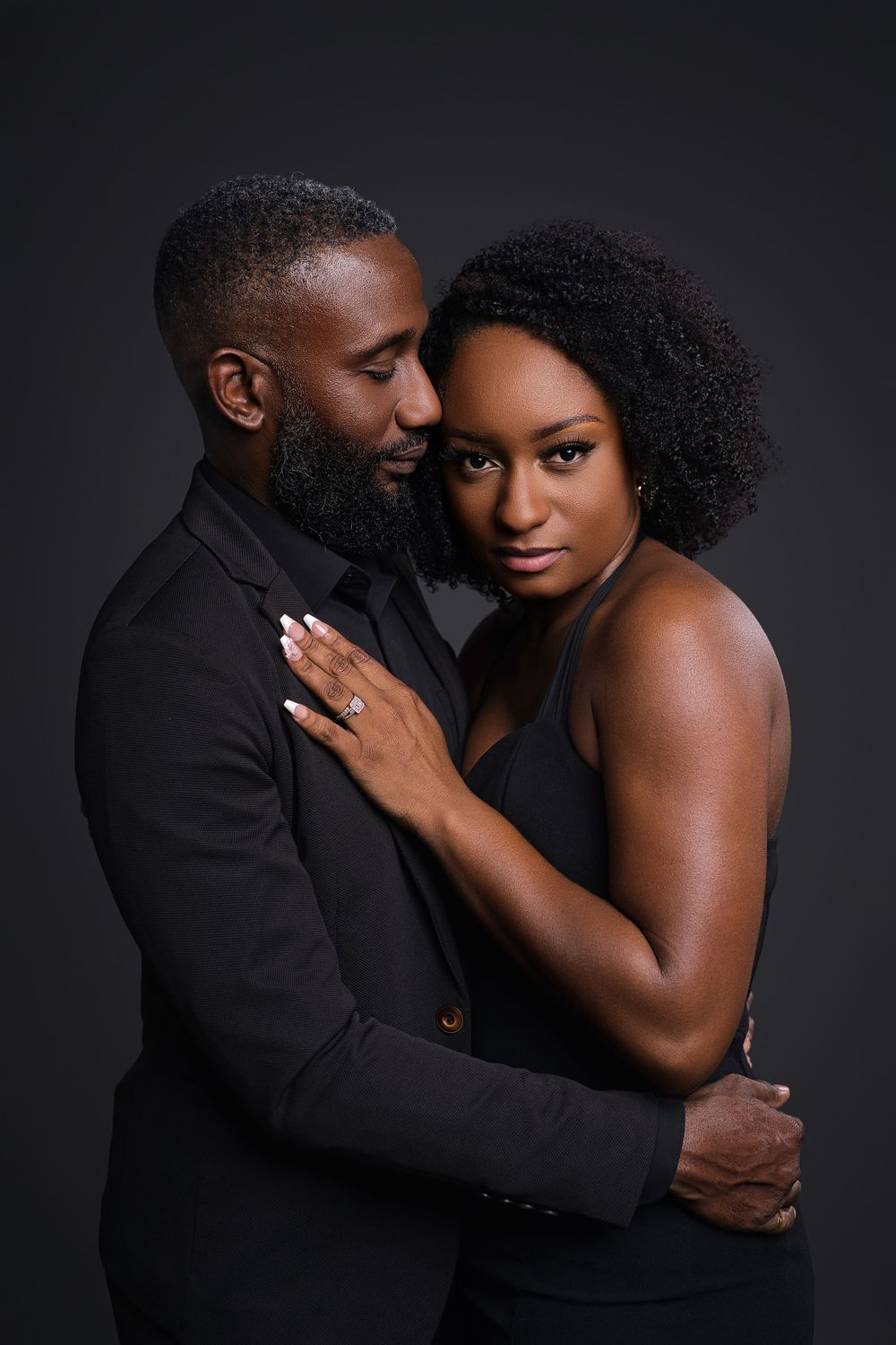 Intimate couple poses together against dark background in romantic boudoir photoshoot series.