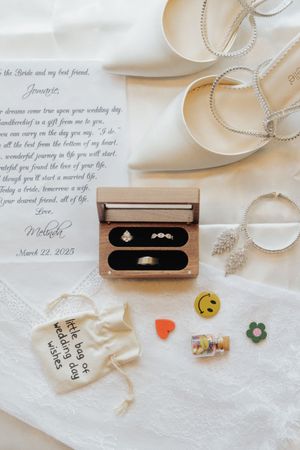 Wedding rings and personal mementos arranged on white linen with handwritten notes.