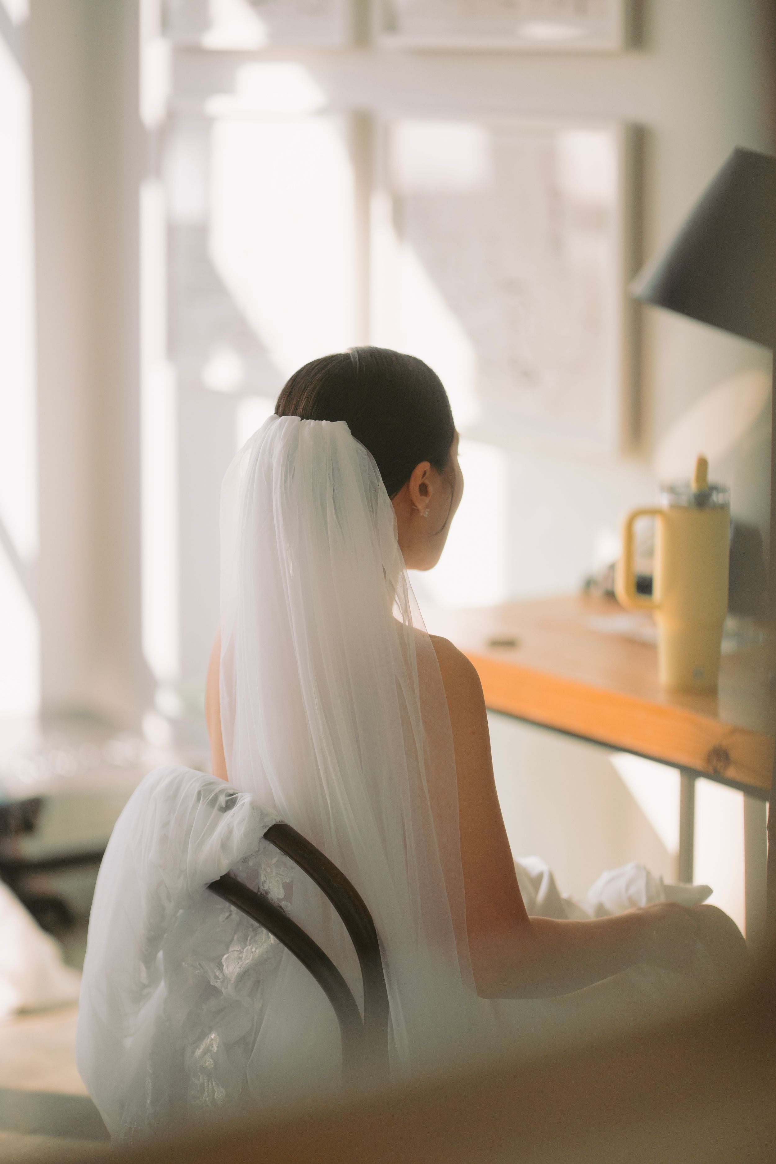 Ethereal bridal preparation scenes with flowing veil in soft window light.