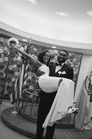 Wedding couple dances joyfully in reception hall with patterned wall backdrop.