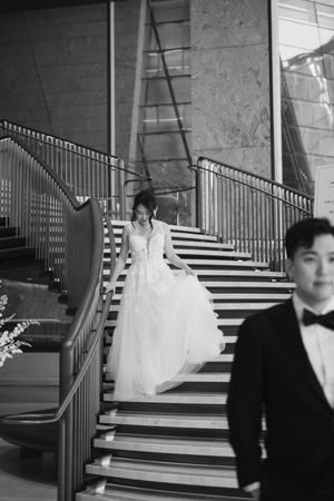Wedding couple descends grand staircase in elegant black and white photography sequence.