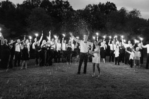 Dramatic nighttime wedding celebration with sparklers creating trails of light.