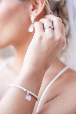 Close-up of bridal jewelry showing diamond ring, pearl bracelet and drop earring.