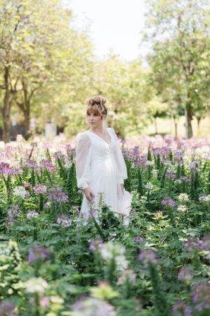 Spring bridal portraits in field of purple wildflowers with soft natural lighting.