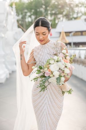 A detailed beaded white wedding dress with delicate floral bouquet.