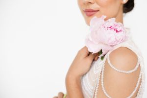 Delicate pearl necklace and pink flower details against a white background.