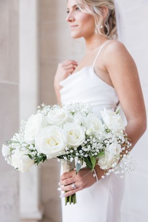 Elegant white rose and baby's breath bridal bouquet against light background.