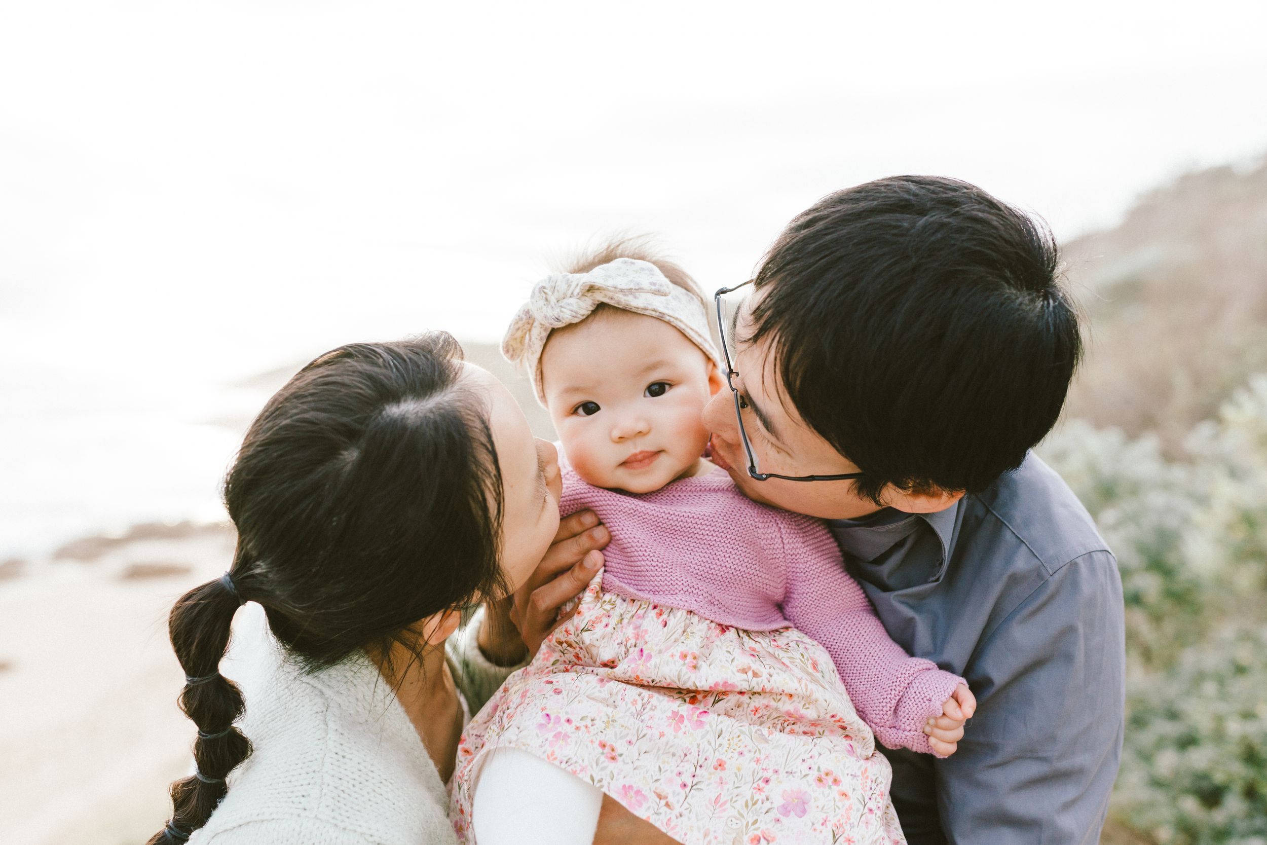 A couple shares tender moments in an outdoor setting with natural scenery in the background.