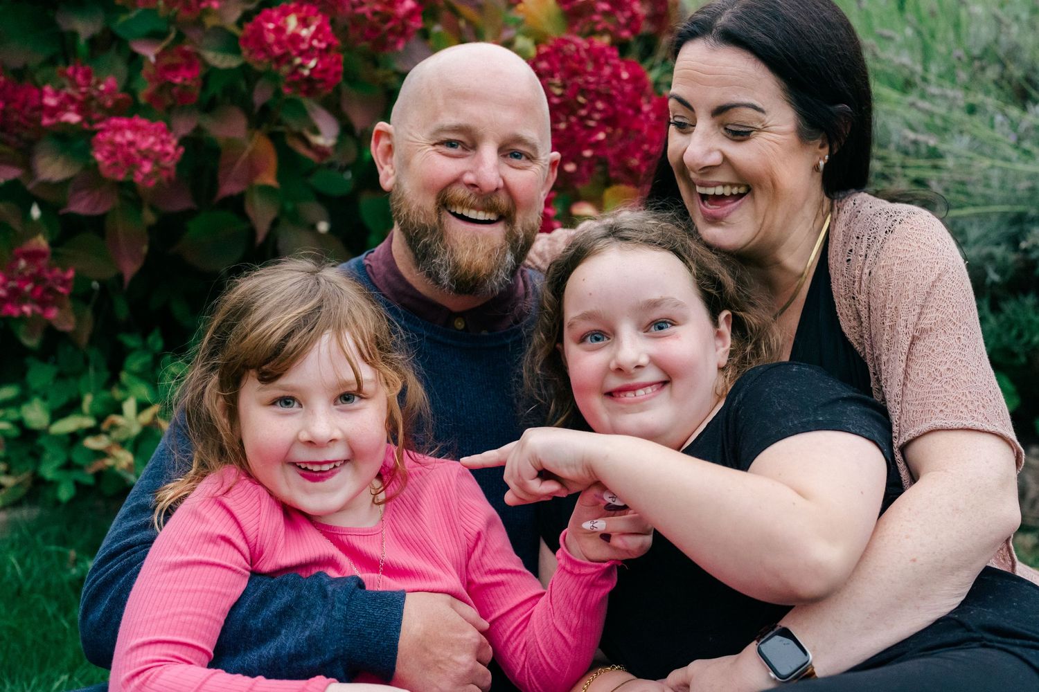 Lifestyle family photography of parents laughing with their children outdoors, photographed naturally during a documentary family session