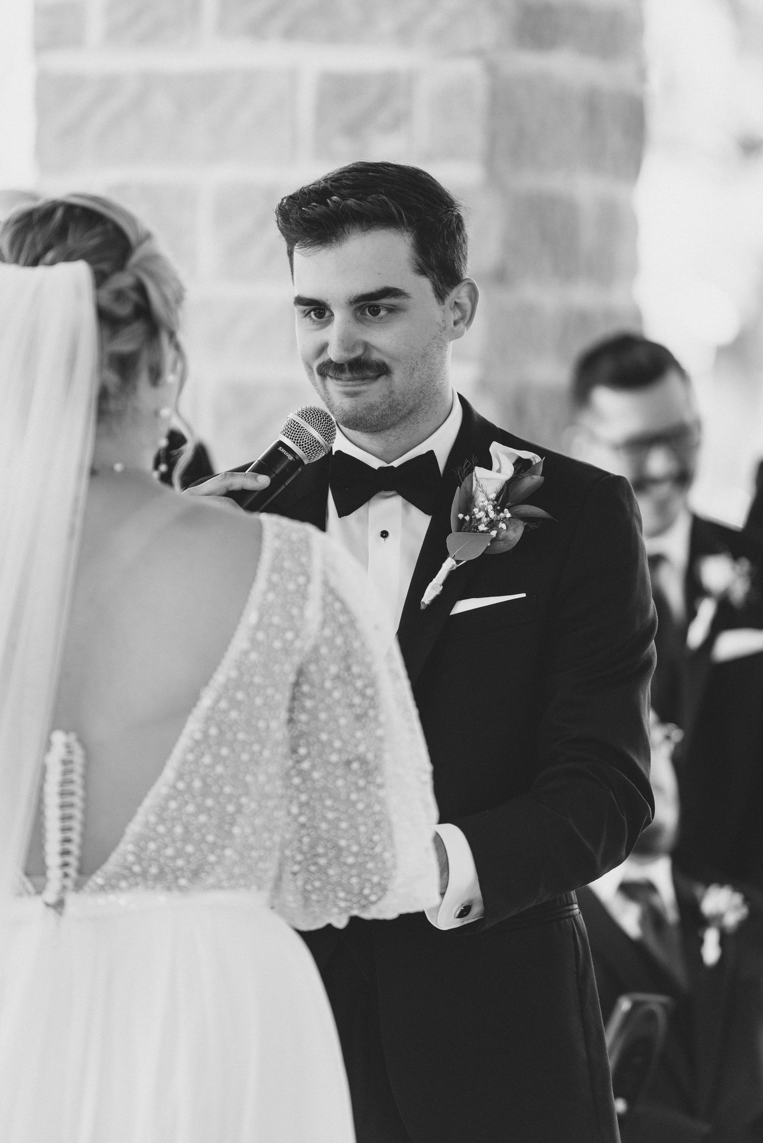 A black and white wedding photo capturing an intimate moment during the ceremony vows.