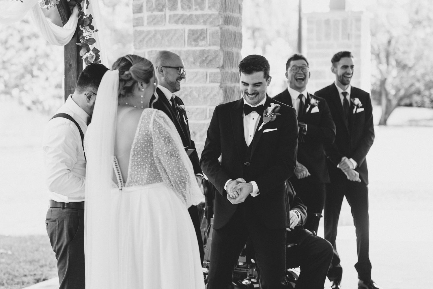A joyful wedding party celebrates outdoors with laughter and smiles during an elegant black and white ceremony.