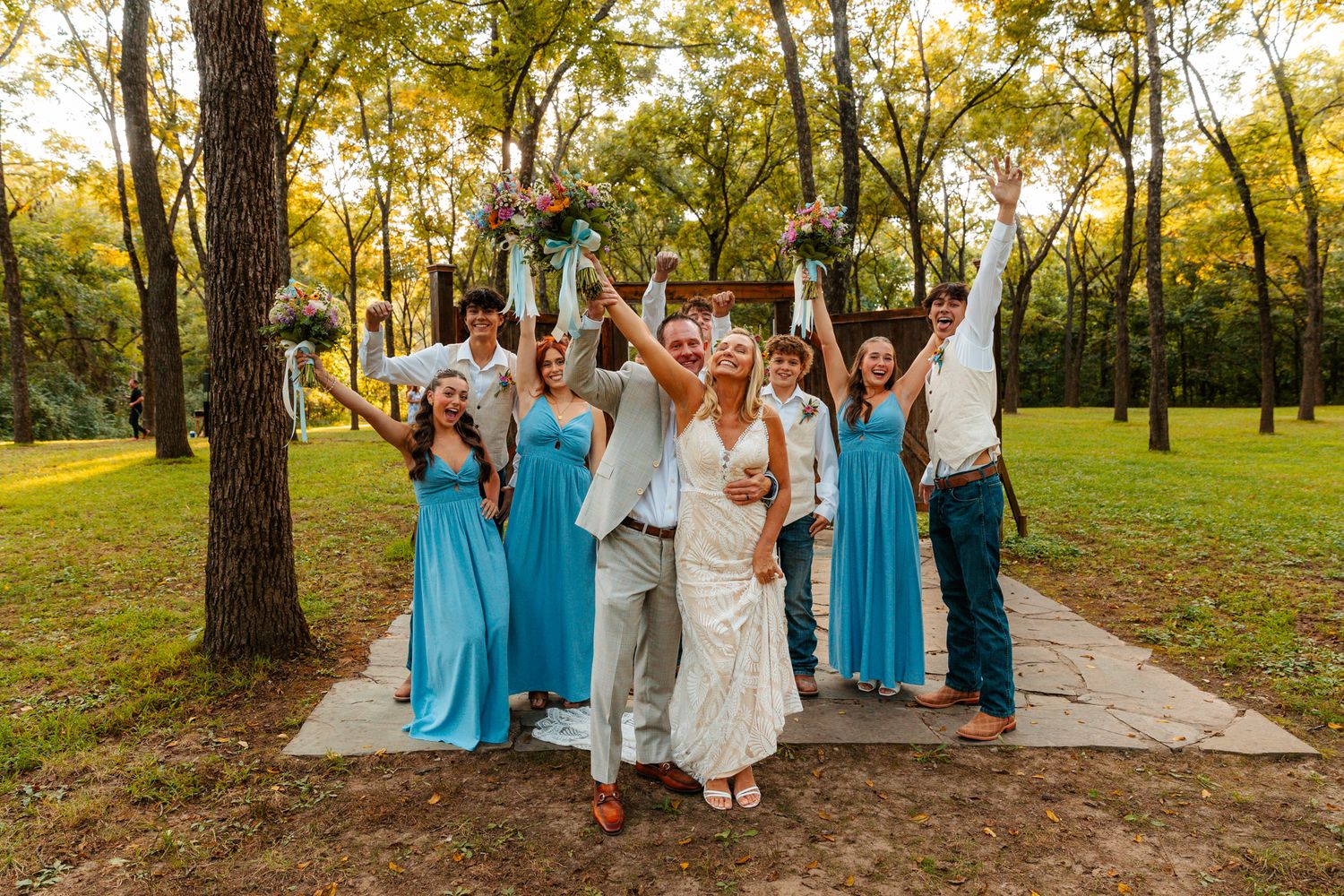 Wedding party in blue dresses and gray suits celebrating on a scenic outdoor path. wedding photography st louis
