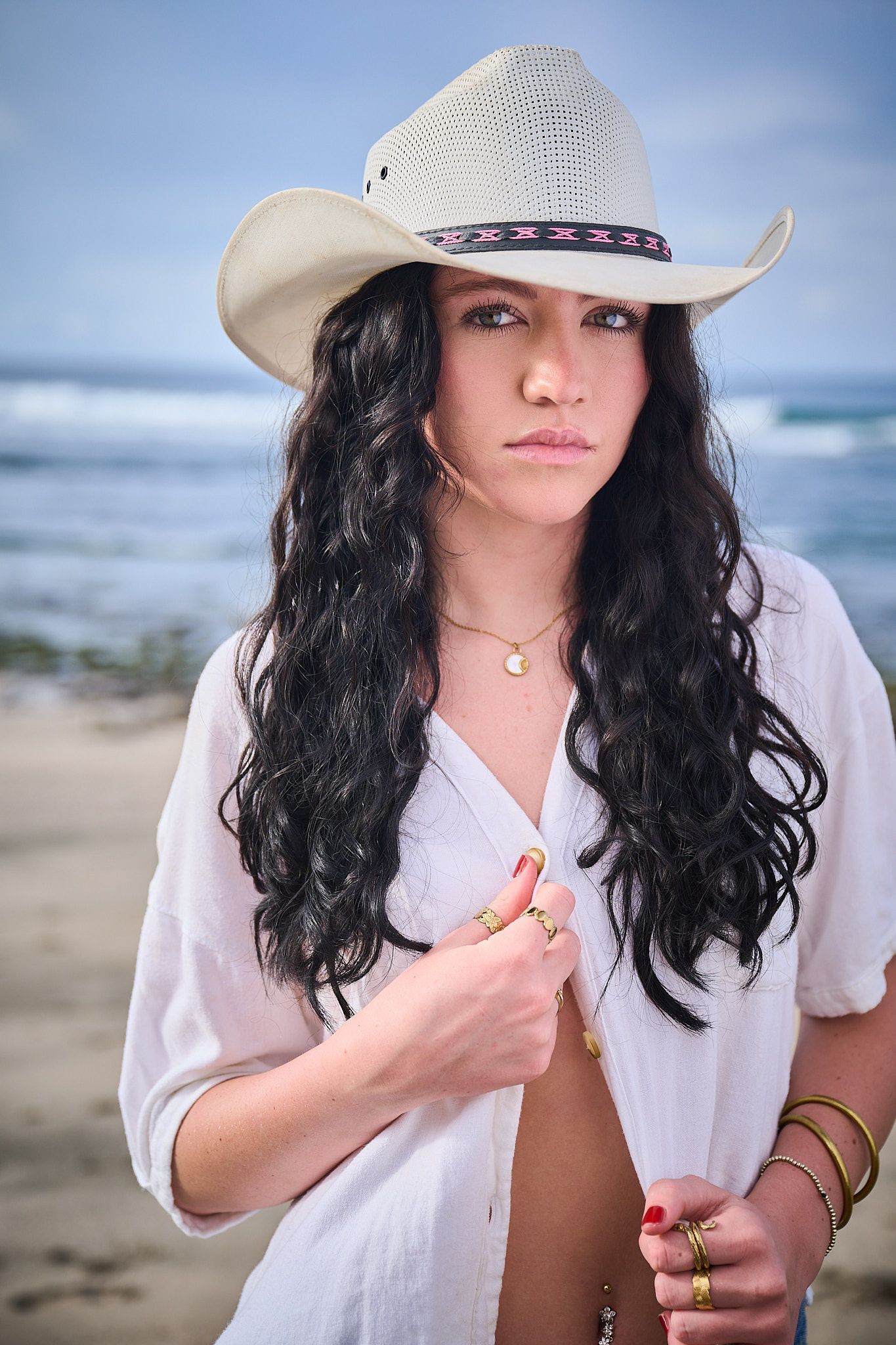A series of beach portraits showing someone in a white shirt and cowboy hat with dark curly hair against an ocean backdrop.