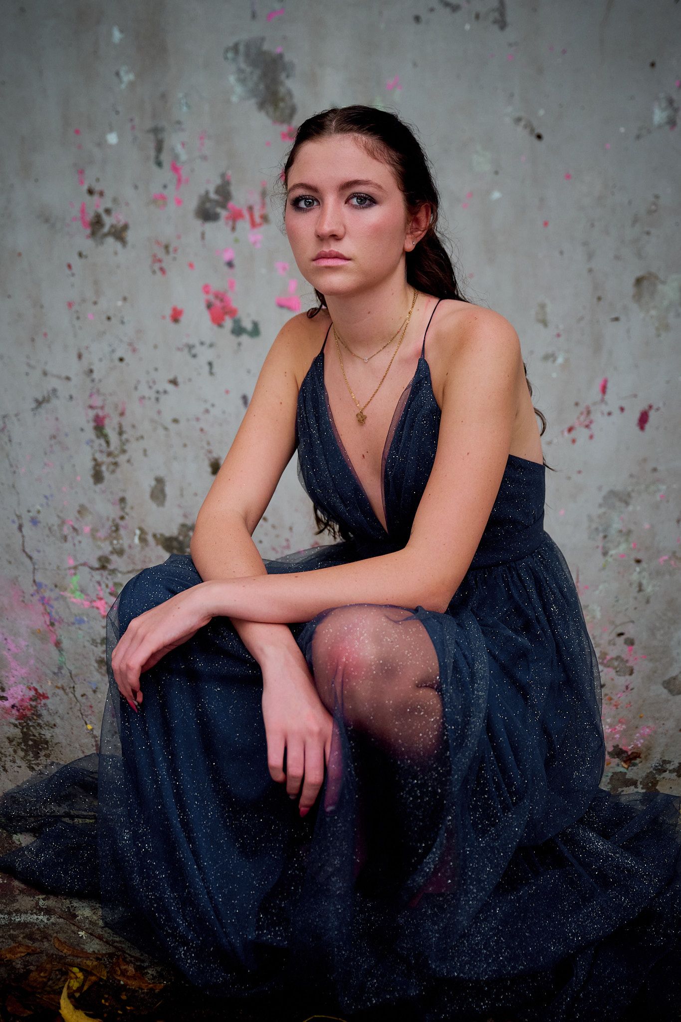 Moody portrait series against textured concrete wall showing person in dark dress with dramatic lighting.