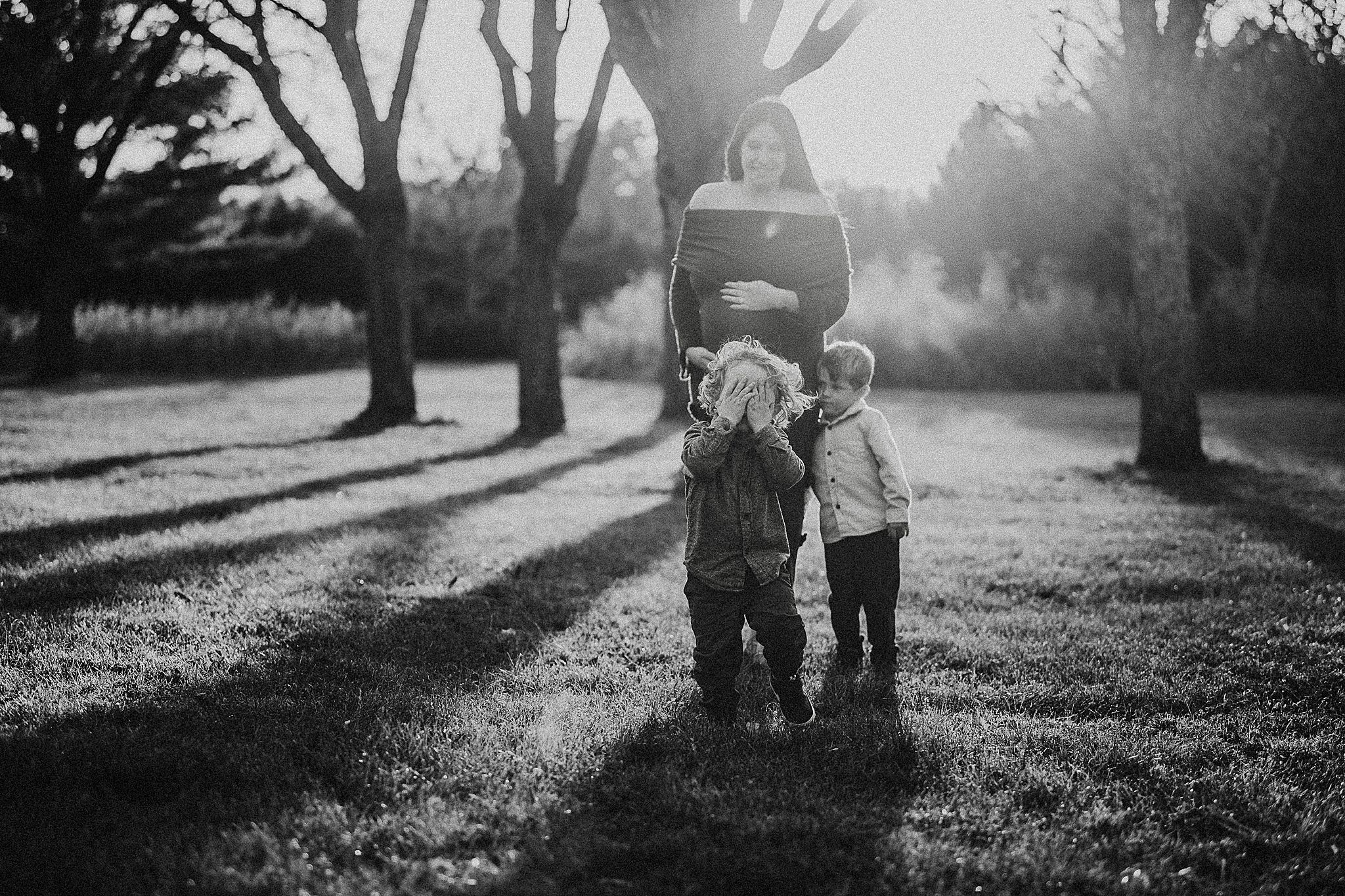 A couple walks together through a sunlit park with long shadows cast across the grass on a peaceful afternoon.