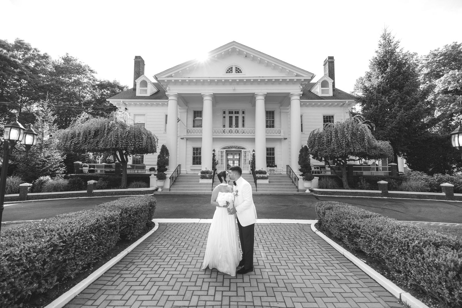 A classic black and white wedding photo in front of a grand white colonial mansion.
