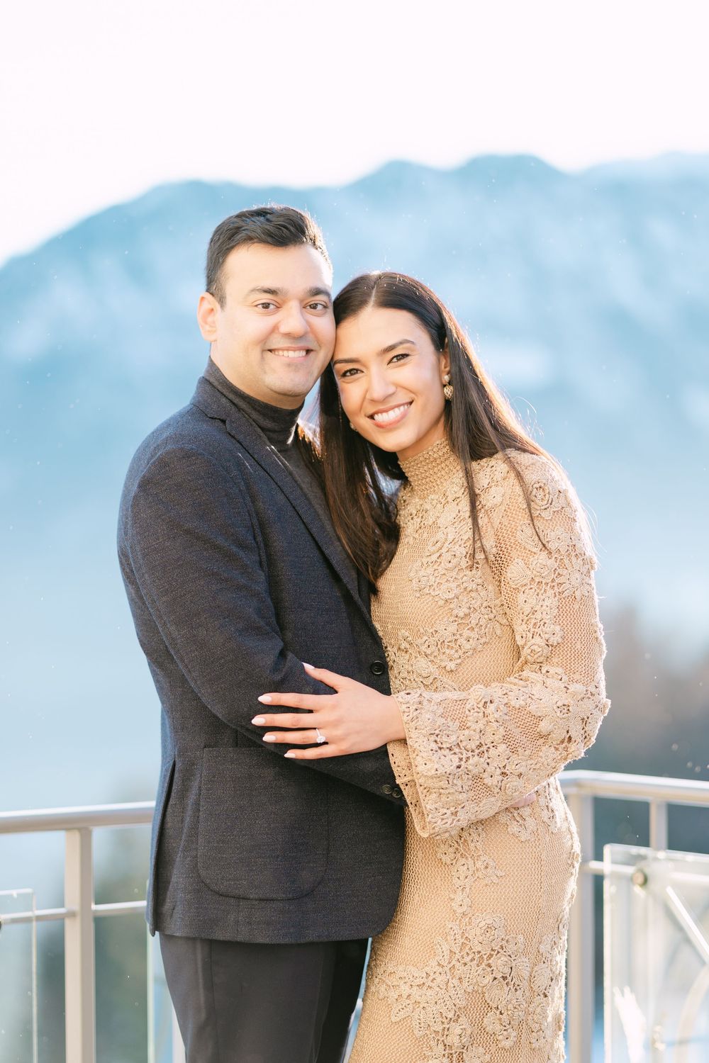 A couple shares a joyful moment on a mountain overlook wearing formal attire.