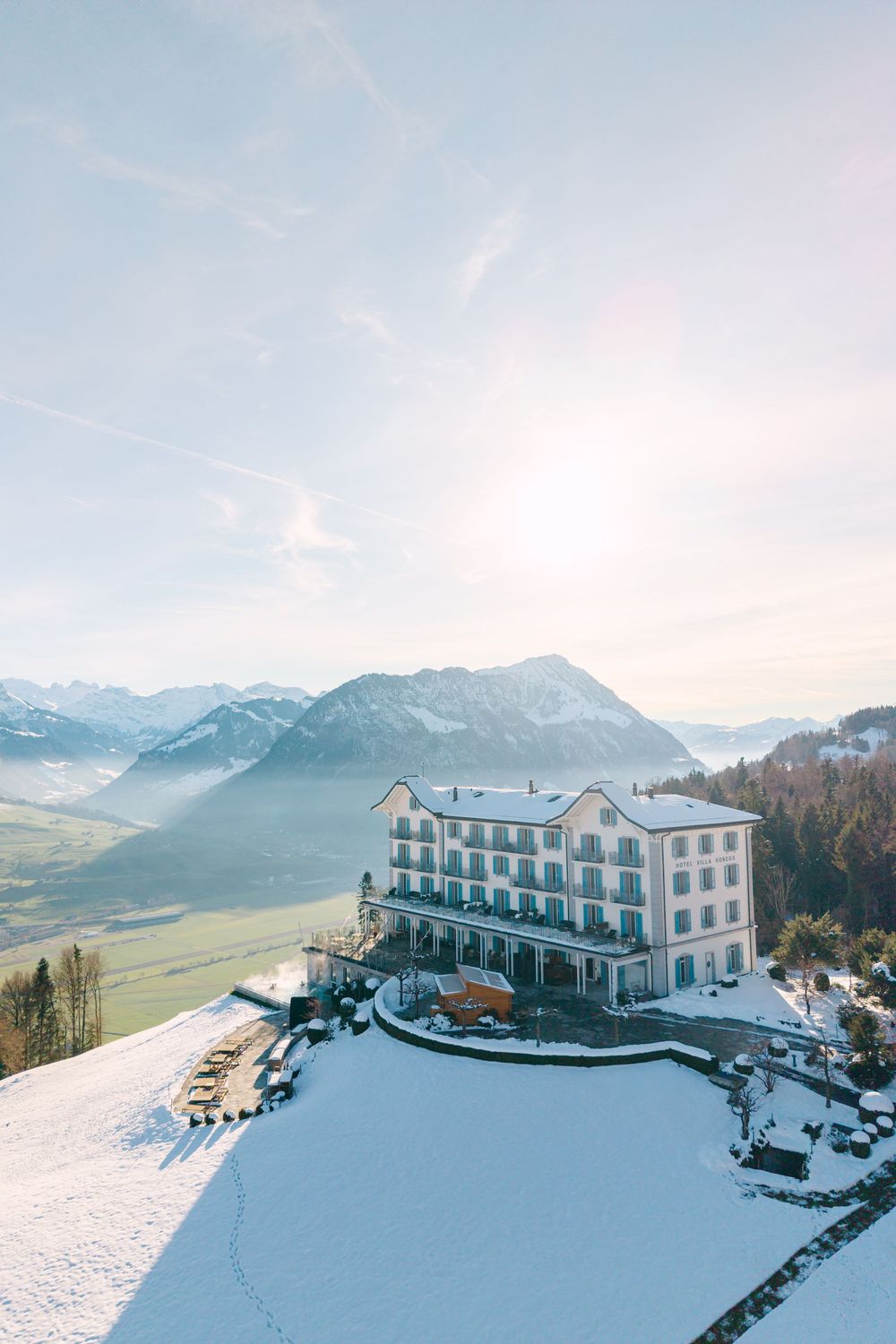 Panoramic view of a snow-covered mountain resort hotel with stunning alpine peaks in the background.