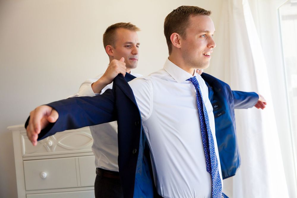 Groomsmen in navy suits and blue ties adjusting their outfits before the ceremony.