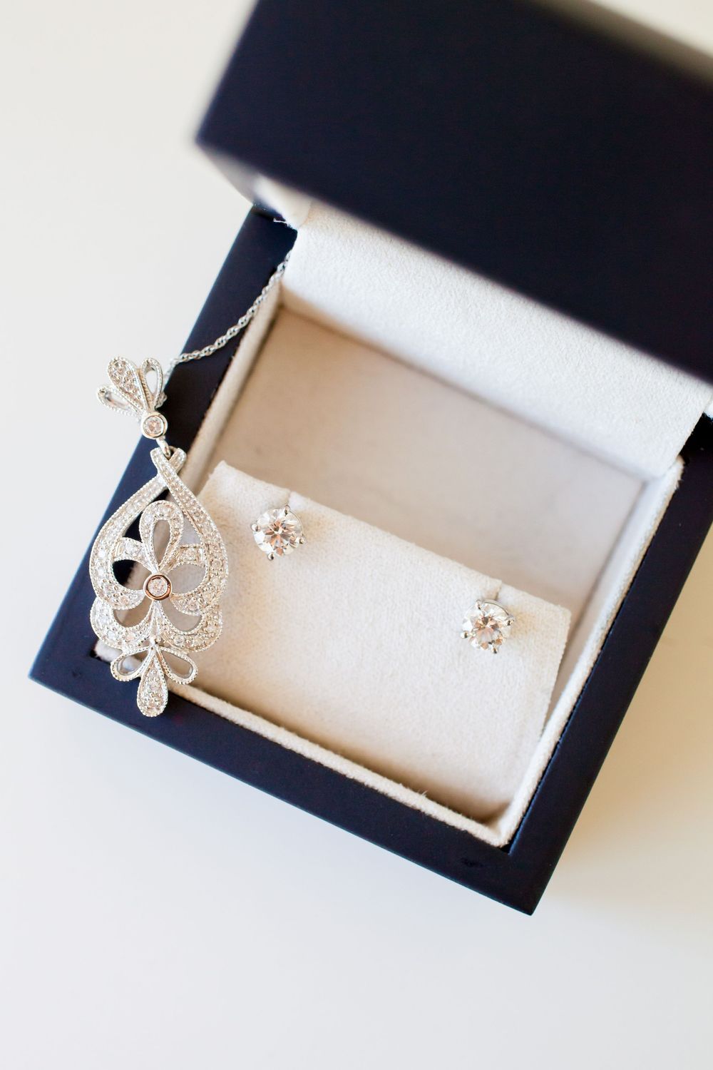 Close-up shots of delicate silver fleur-de-lis earrings displayed in a jewelry box.