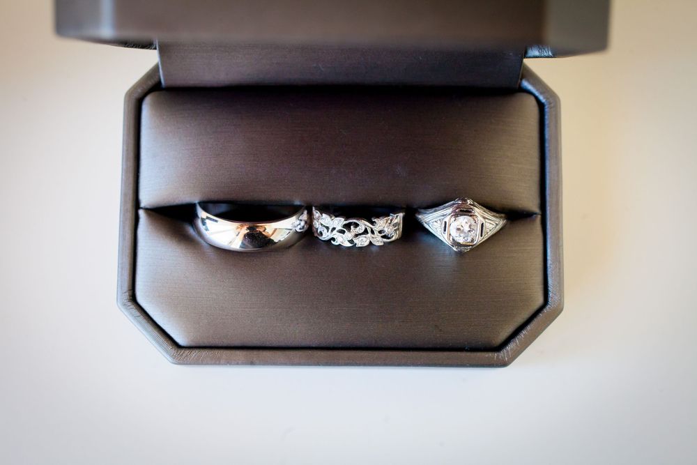 Three diamond engagement rings arranged on a dark surface with dramatic lighting.