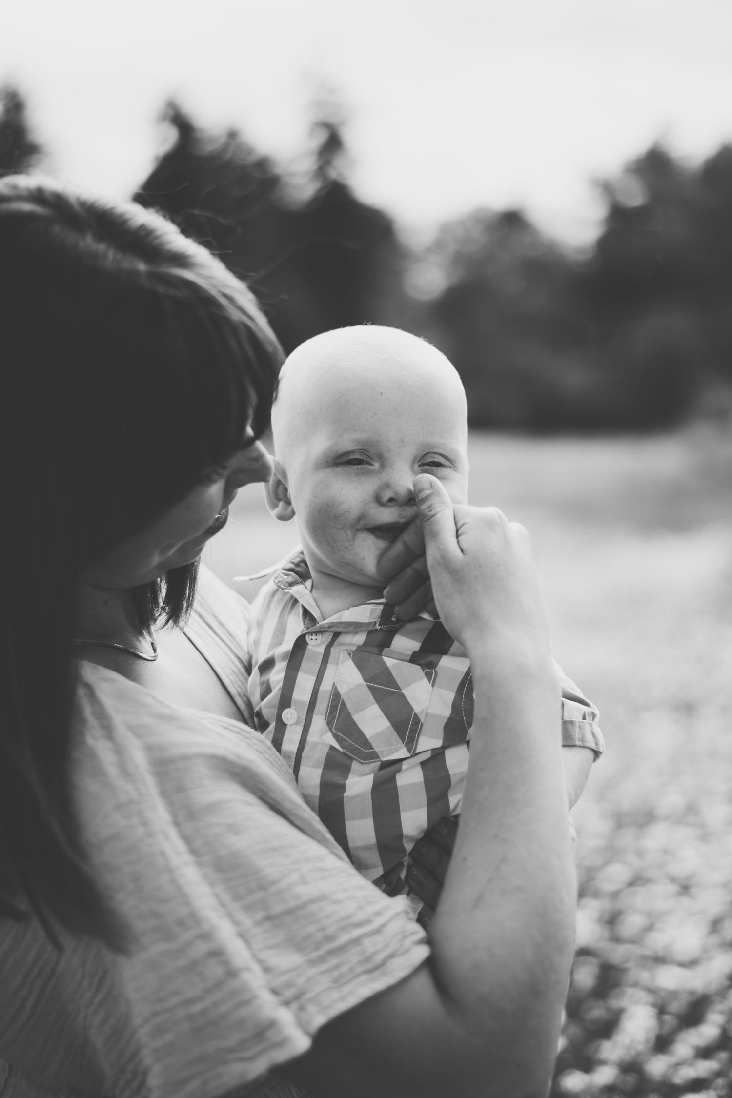 Black and white sequence of a parent and baby sharing tender moments together in a natural outdoor setting.