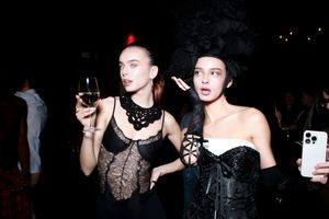 Two people in gothic party attire holding phones at a nightclub event.